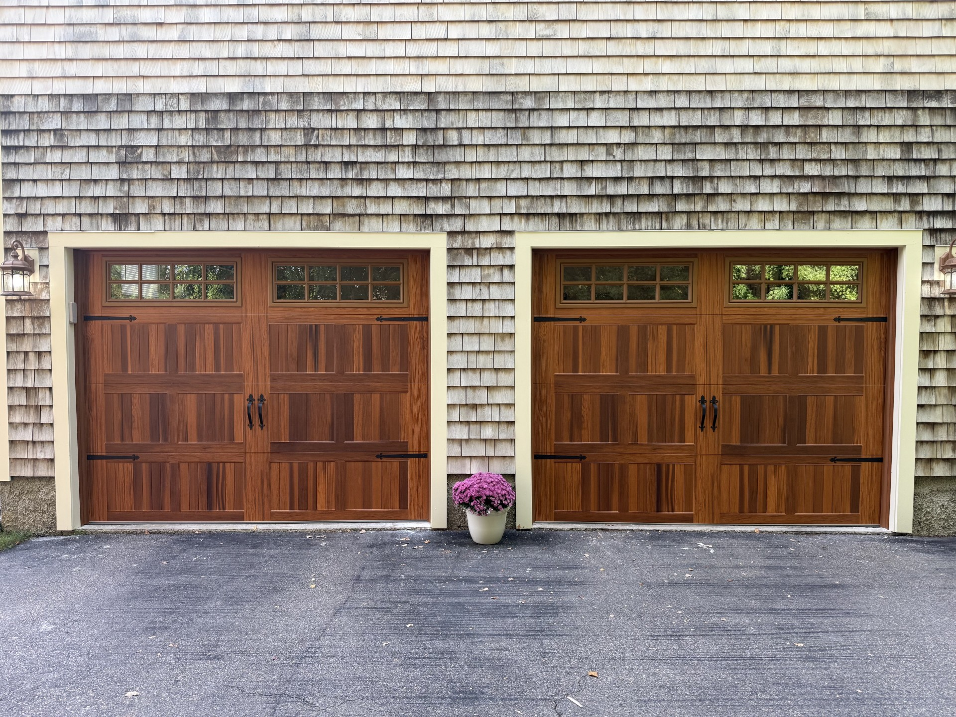 Two wood carriage-style garage doors on a shingle-sided home