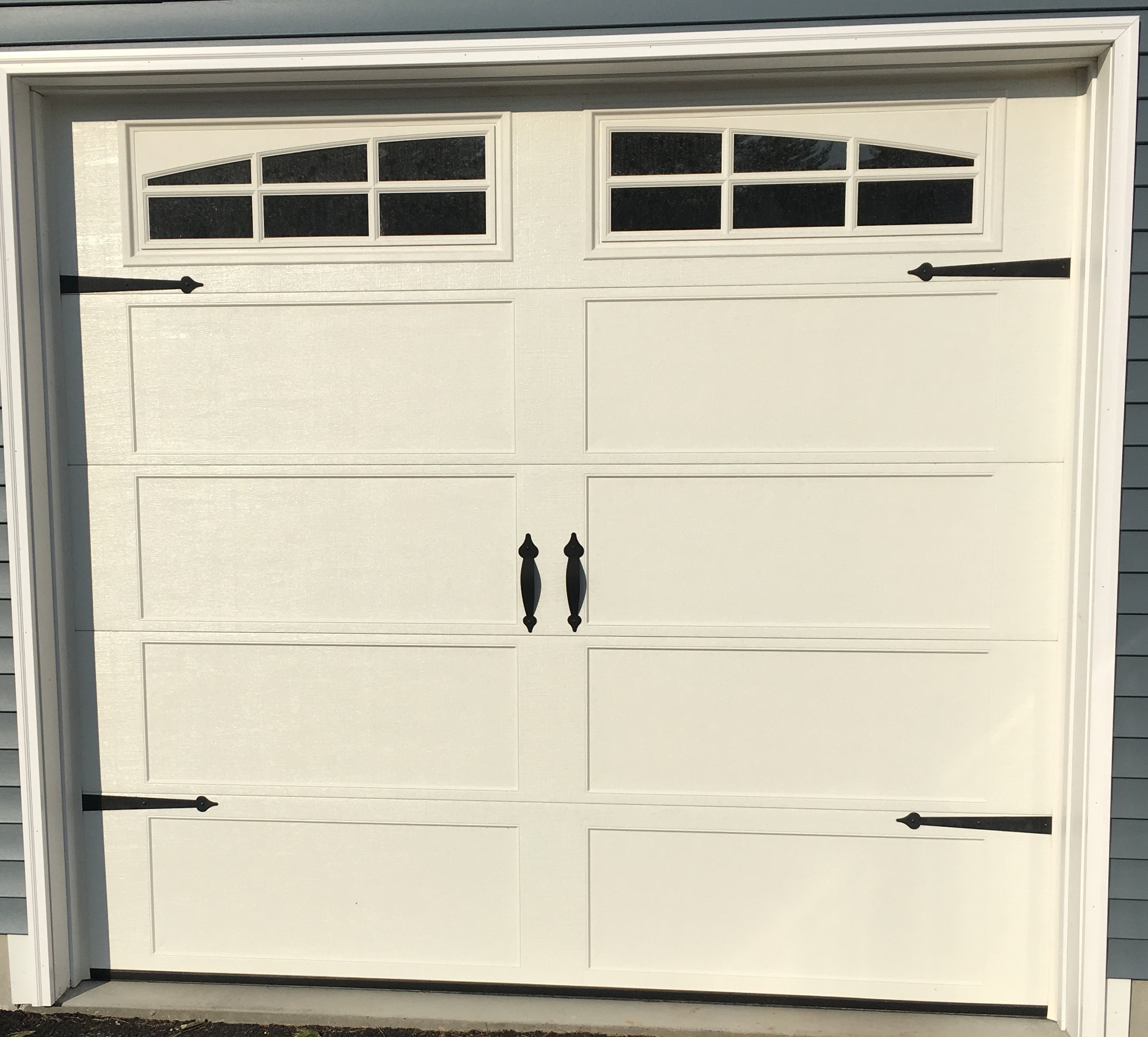 Recessed-panel garage door with arched glass inserts and decorative hardware